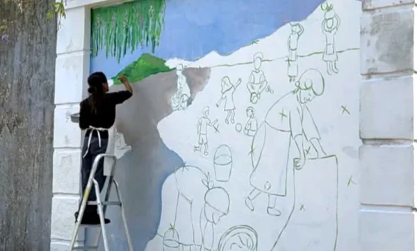 Dos imágenes muestran el proceso de creación del mural en el Parque Zorrilla y su resultado final, con las flores incorporadas por escolares en homenaje al barrio Cuchilla de las Flores.